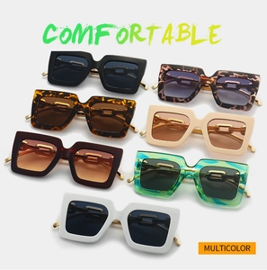 Détail de lunettes de soleil carrées avec branches à chaîne dorée en plusieurs couleurs