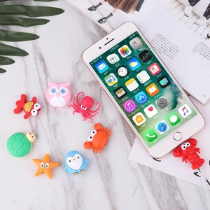 Group of colorful animal silicone cable protectors on marble background with lifestyle props