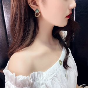 Detail of vintage green circular studs with double layered gold rings on a model