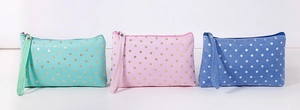 Detailed view of mint, pink, and blue fabric pouches with gold polka dots and wrist straps