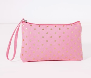 Detail of pink fabric cosmetic bag featuring gold polka dots and matching wrist strap