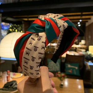 Detail of knotted silk-satin headband with green-red stripes and chic pattern
