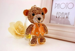 Close-up of sparkling rhinestone bear keychain featuring orange vest and floral details