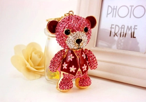 Close-up of cute teddy bear keychain with pink rhinestones and a floral red vest