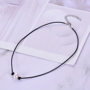 Detail of single white freshwater pearl on black leather cord with silver lobster clasp