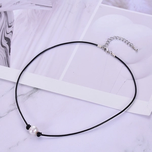 Detail view of a single white freshwater pearl on black leather cord with silver clasp