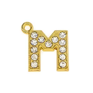 Macro shot of 15mm gold letter M pendant encrusted with white rhinestones for DIY jewelry