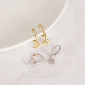 Detailed view of silver and gold S925 moon and star earrings with pavé crystals