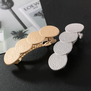 Détail de barrettes en alliage or et argent mat avec quatre disques ronds à texture mate