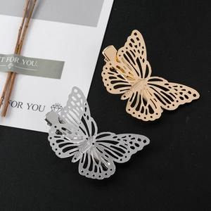 Macro detail of gold and silver hollow metal butterfly hair clips with laser-cut veins