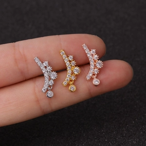 Trois clous d'oreilles fleur en zircon argenté, doré et or rose posés sur un doigt