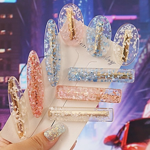 Detailed macro view of resin hair clips with colorful sequins and golden alloy bases