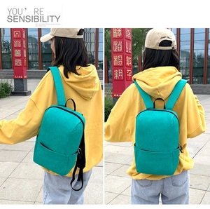 Detail view of a compact lake blue oxford backpack with zip pocket on outdoor model