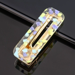 Detailed close-up of acetate hair clip with purple and green sequins on gold metal base
