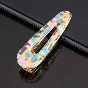Macro view of oval acetate hair clip with colorful speckles and gold plated metal base