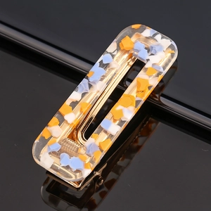 Macro detail of rectangle acetate hair clip showing colorful fragments and gold metal base
