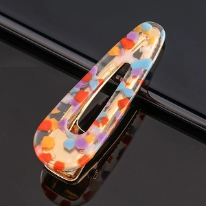 Macro shot of an oval hollow acetate hair clip with colorful confetti and gold metal clip