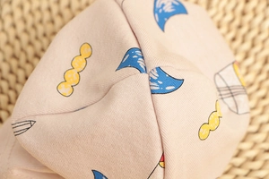 Close-up of soft cotton knit fabric with colorful cartoon pencil prints for baby hats