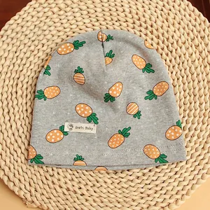 Detailed knit texture of light grey baby beanie with orange carrot patterns