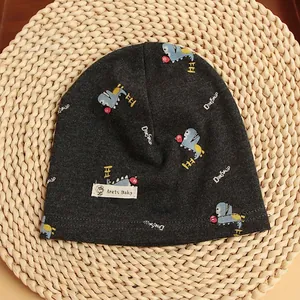 Detail of dark grey cotton baby beanie with dinosaur prints on woven background