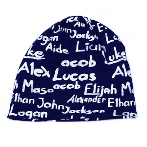 Detail of navy knit beanie featuring white handwritten graffiti style letter patterns