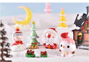 Macro shot of miniature Christmas resin figures including Santa and snowman on snow