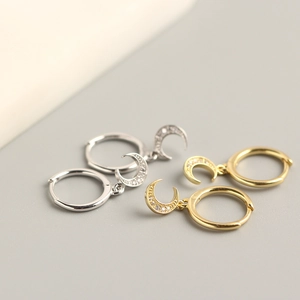 Detail of silver and gold crescent moon hoop earrings with crystal pavé settings