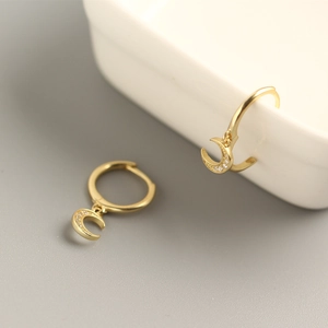 Macro view of gold crescent moon hoop earrings with pavé sparkling cubic zirconia stones