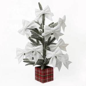 White Christmas bows with silver glitter hanging on a small tree for festive holiday decor