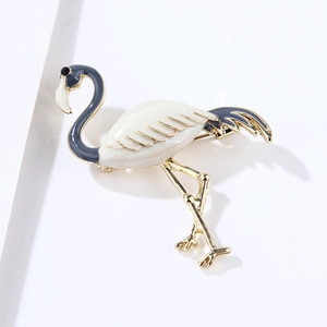 Close-up of golden flamingo brooch with white enamel inlay and grey-blue feather details