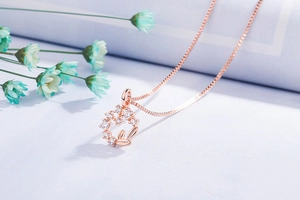 Close-up of rose gold leafy pendant with sparkling pavé crystals on a dainty chain