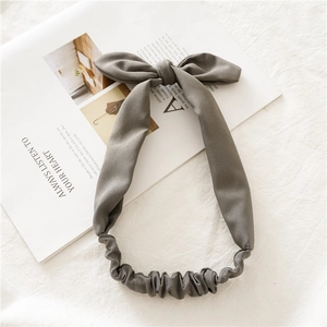 Detail of grey elastic bunny ear headband with a large knot bow on a fabric background