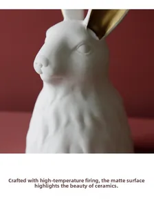 Detail of matte white ceramic rabbit vase with gold ears and handcrafted texture