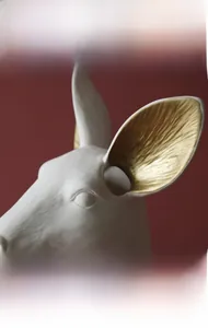 Detail of matte white ceramic deer head vase with elegant gold interior ear accents
