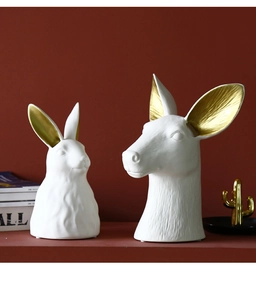 Detailed view of matte white ceramic animal head vases with elegant gold ear accents