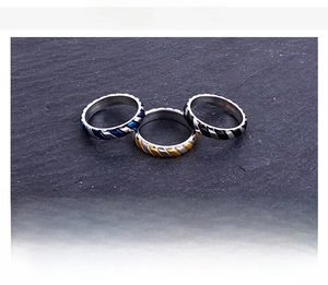 Close-up of three stainless steel rings with twisted rope texture in gold blue and black