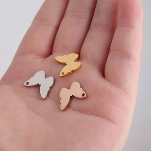 Mirror polished butterfly charms in gold, silver, and rose gold on a palm
