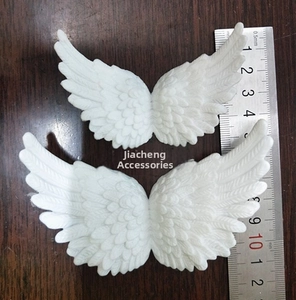 Close-up of white plastic angel wings with feather texture and ruler for scale