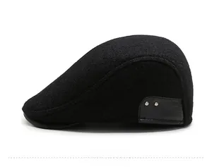 Detail view of black wool beret cap featuring leather patch and silver metal rivets