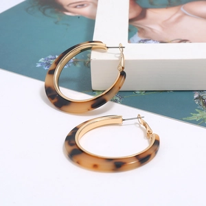 Detailed close-up of leopard print acetate C-hoop earrings with golden metal borders
