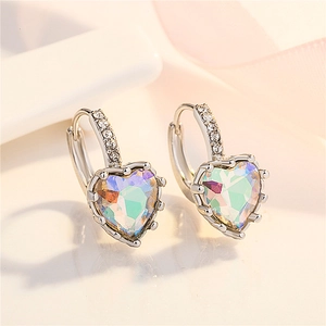 Macro detail of silver heart-shaped earrings with colorful gemstone and pavé diamonds