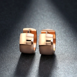 Macro shot of polished rose gold stainless steel hoop earrings on dark textured background