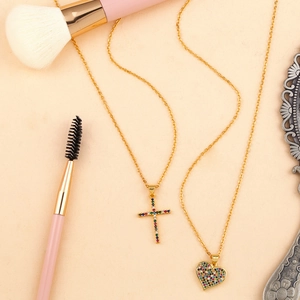 Gold cross and heart pendant necklaces with colorful zircon stones on a beige background