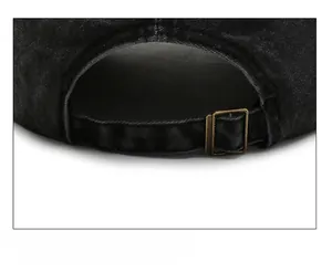 Detail view of washed black denim baseball cap with adjustable bronze metal buckle strap