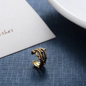 Macro view of vintage gold thorn ear cuff with intricate carved texture on a blue background