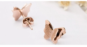 Vista detallada de pendientes de mariposa en oro rosa con acabado mate arenado