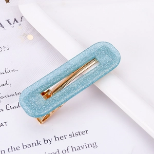 Detail view of light blue acetate hair clip with glitter finish and gold metal spring clip