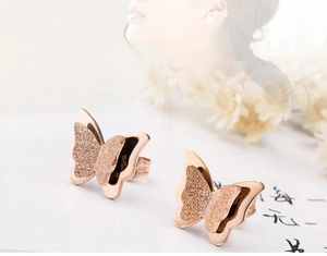 Detalle de pendientes de mariposa en oro rosa con texturas mate y pulidas en capas