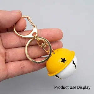 Golden keychain with D-ring and large hollow star yellow bell on neutral background