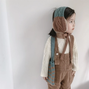Detail of teal and brown knitted earmuffs with faux fur lining and matching crossbody bag